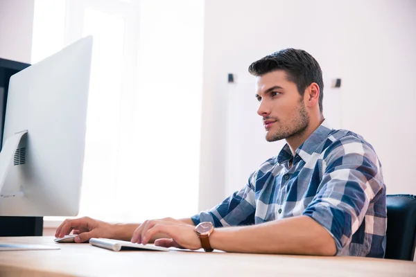 Selbstbewusster Geschäftsmann mit PC am Tisch — Stockfoto