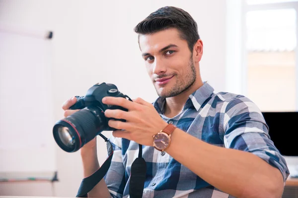 Glücklicher Mann sitzt mit Fotokamera am Tisch — Stockfoto