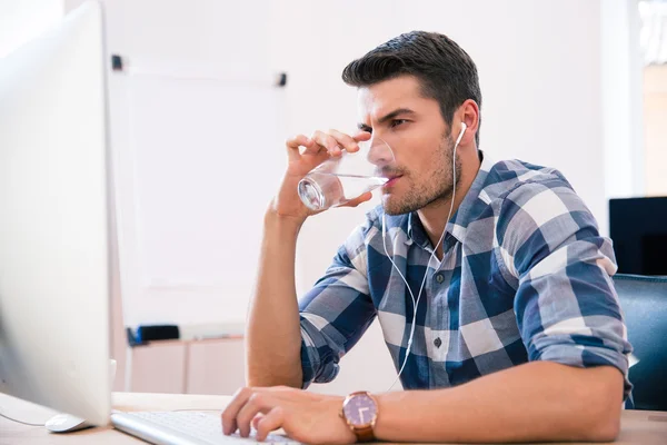 Красивый бизнесмен пьет воду в офисе — стоковое фото