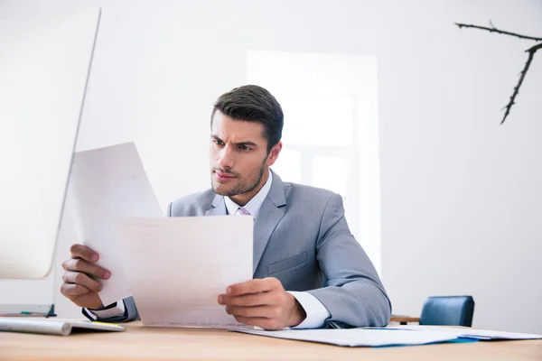 Empresario leyendo papeles en la oficina —  Fotos de Stock