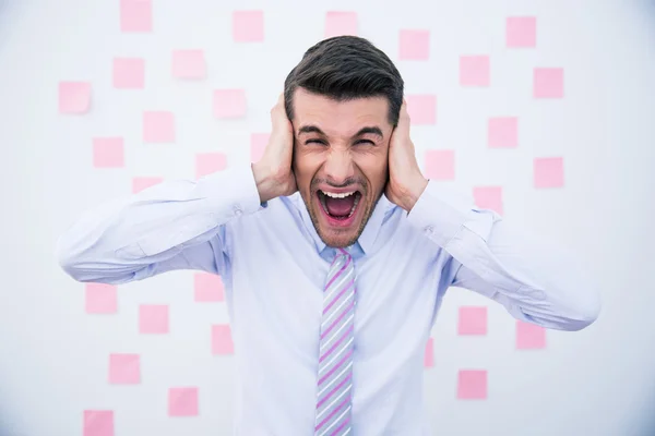 Zakenman die betrekking hebben op zijn oren en schreeuwen — Stockfoto