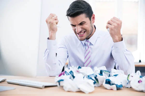 Empresário sentado à mesa com papel amassado — Fotografia de Stock