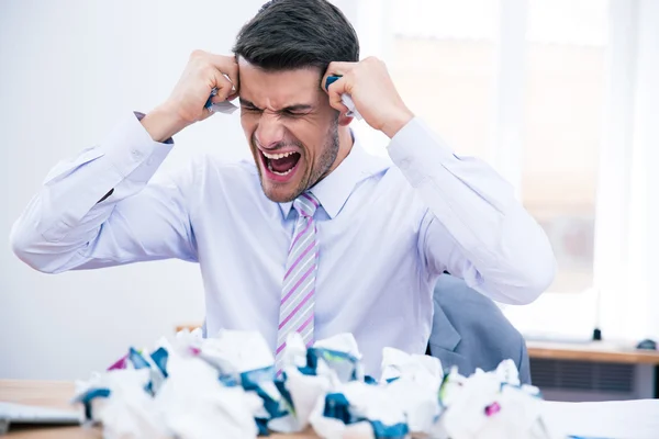 Empresário sentado à mesa com papel amassado — Fotografia de Stock