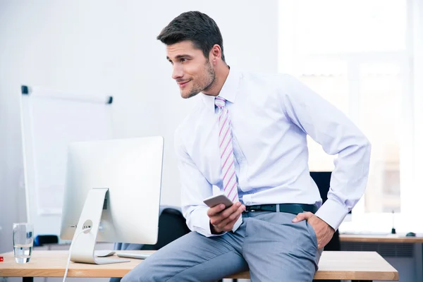 Empresário sentado na mesa e usando smartphone — Fotografia de Stock