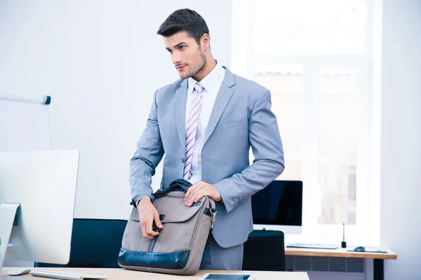 Красивый бизнесмен закрывает сумку на столе — стоковое фото