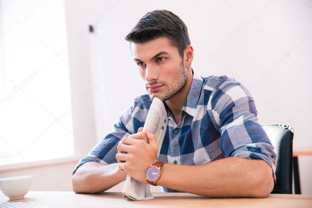 Pensive casual businessman sitting at the table