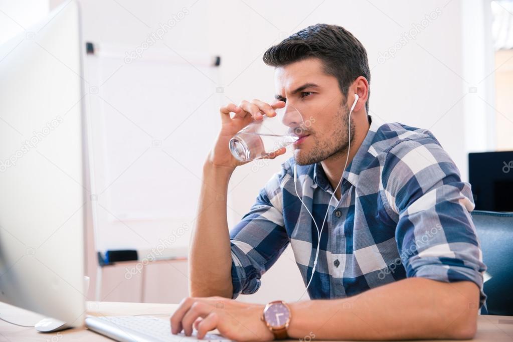 Handsome businessman drinking water in office