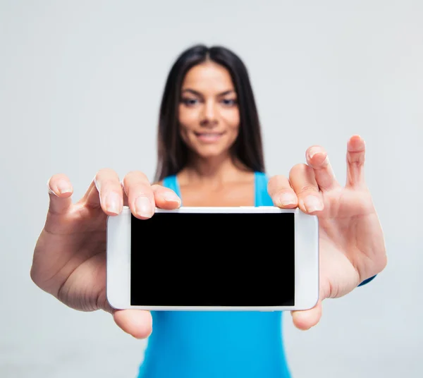 Улыбающаяся женщина показывает чистый экран смартфона — стоковое фото