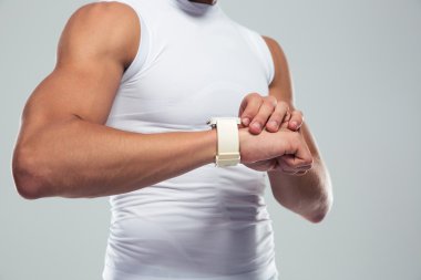 Closeup portrait of a muscular man using smartwatch