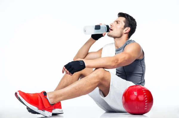 Fitness muž sedí na podlaze a pitné vody — Stock fotografie