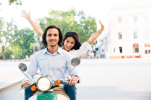 Cheerful couple riding on a scooter — Stock Photo, Image