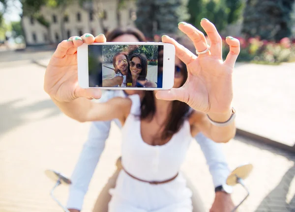 Casal mostrando tela do smartphone ao fazer selfie — Fotografia de Stock