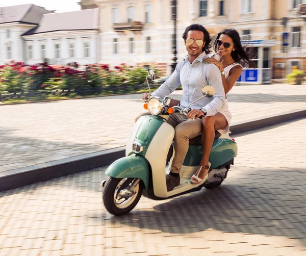 Coppia felice cavalcando su uno scooter — Foto Stock