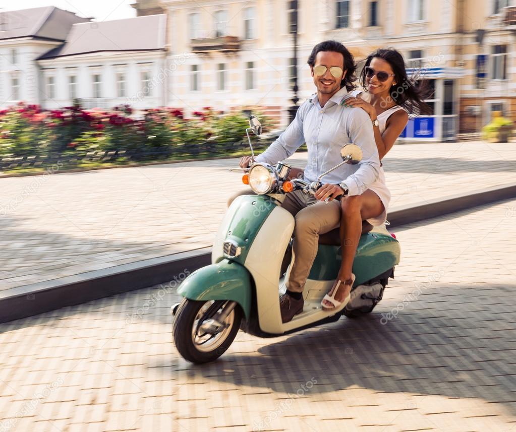 Happy couple riding on a scooter