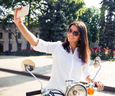 woman on scooter making selfie photo