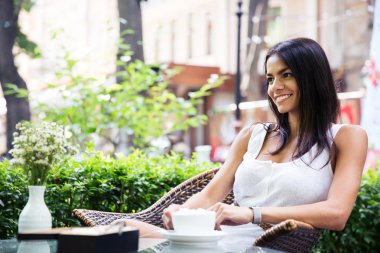 Happy young woman sitting in outdoors cafe