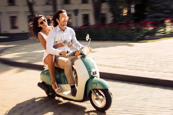 Allegro giovane coppia cavalcando uno scooter — Foto Stock
