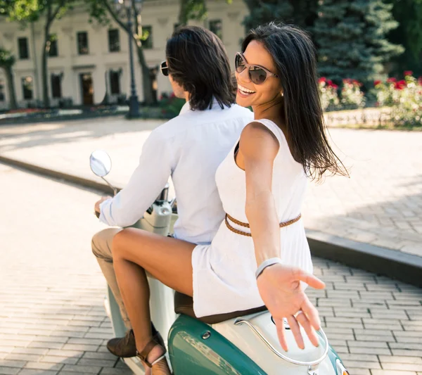 Смеющаяся пара едет на скутере — стоковое фото