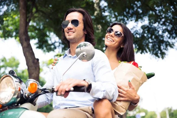 Happy young couple riding a scooter — Stockfoto