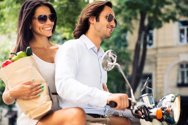 Sorridente giovane coppia cavalcando uno scooter — Foto Stock
