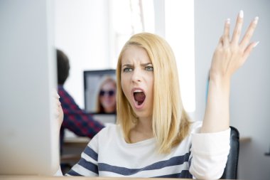 Shocked young woman working on computer