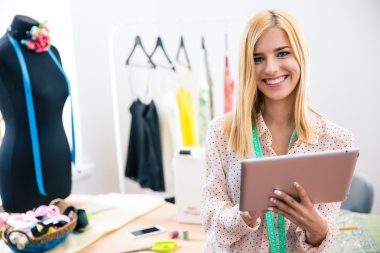 Happy female tailor holding tablet computer 