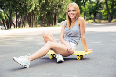 Mutlu genç kız siiting kaykay üzerinde