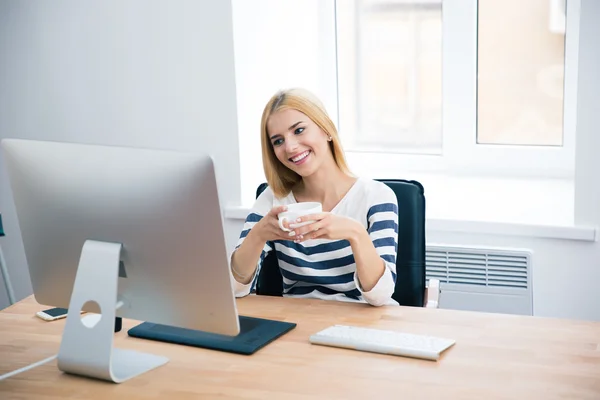 Happy female designer drinking coffee in office — Stock fotografie