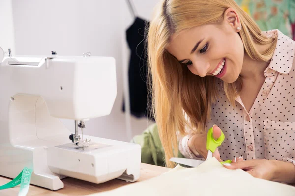 Happy female tailor cutting cloth — Stock fotografie