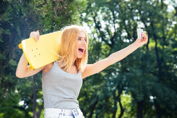 Chica con monopatín haciendo foto selfie en smartphon —  Fotos de Stock