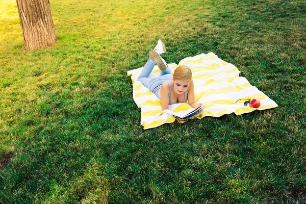 Donna sdraiata su tappetino e libro di lettura — Foto Stock
