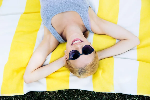 Sorridente giovane donna sdraiata sul tappeto — Foto Stock