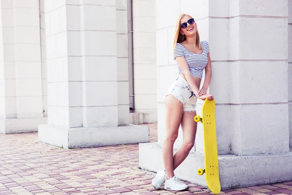Sexy female teenager in sunglasses holding skateboard — Stock Photo, Image