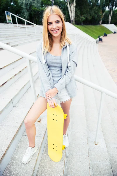 Teenager girl standing on stairs with skateboard — Stockfoto