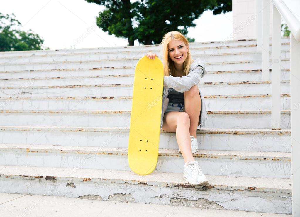 Young girl sitting on the stairs with skateboard
