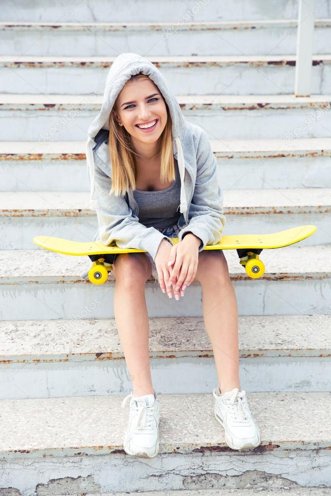 girl sitting on the stairs with skateboard