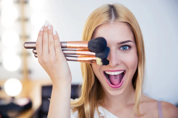 Woman covering her eye with brushes — Stock Photo, Image