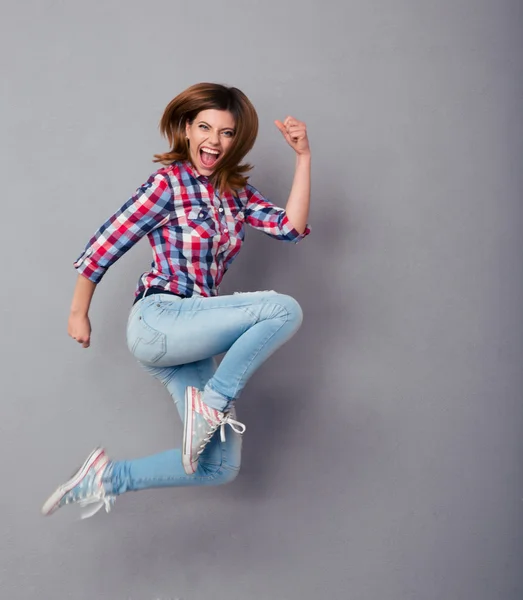 Aufgeregte Frau springt isoliert auf einem grauen — Stockfoto