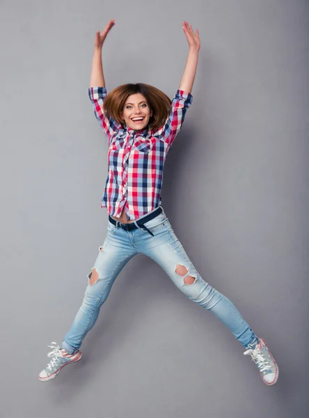 Lächelnde junge Frau springt isoliert auf grau — Stockfoto