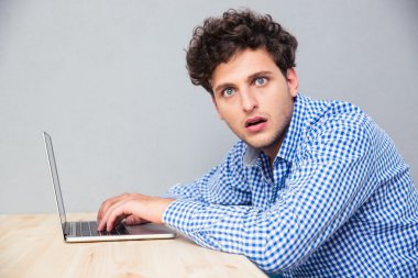 Laptop ile masada oturan şok adam 