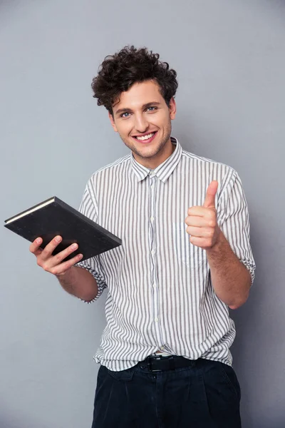 Mann hält Buch und zeigt Daumen hoch — Stockfoto