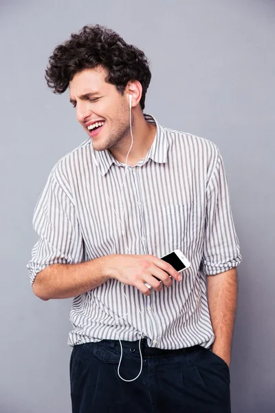 Hombre escuchando música en auriculares en el teléfono inteligente — Foto de Stock