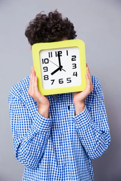 Uomo che si copre il viso con grande orologio — Foto Stock