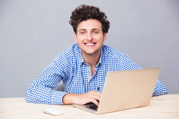 Hombre alegre sentado en la mesa con el ordenador portátil —  Fotos de Stock