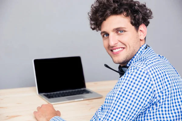 Laptop ile masada oturan gülümseyen adam — Stok fotoğraf