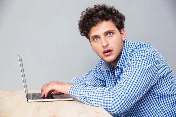 Homem chocado sentado à mesa com laptop — Fotografia de Stock