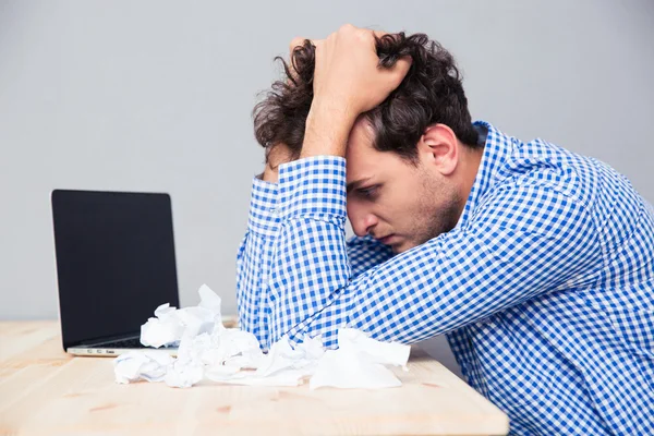 Empresario con laptop y papeles arrugados — Foto de Stock