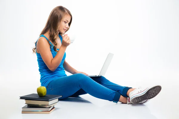 Chica sentada en el suelo con el ordenador portátil y beber café —  Fotos de Stock