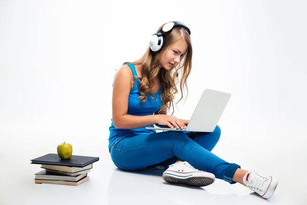 Kvinna med hörlurar och använder laptop på golvet — Stockfoto