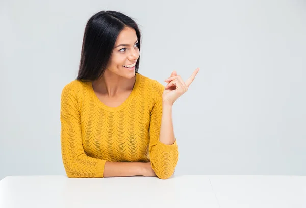 Mujer sentada a la mesa y señalando con el dedo —  Fotos de Stock